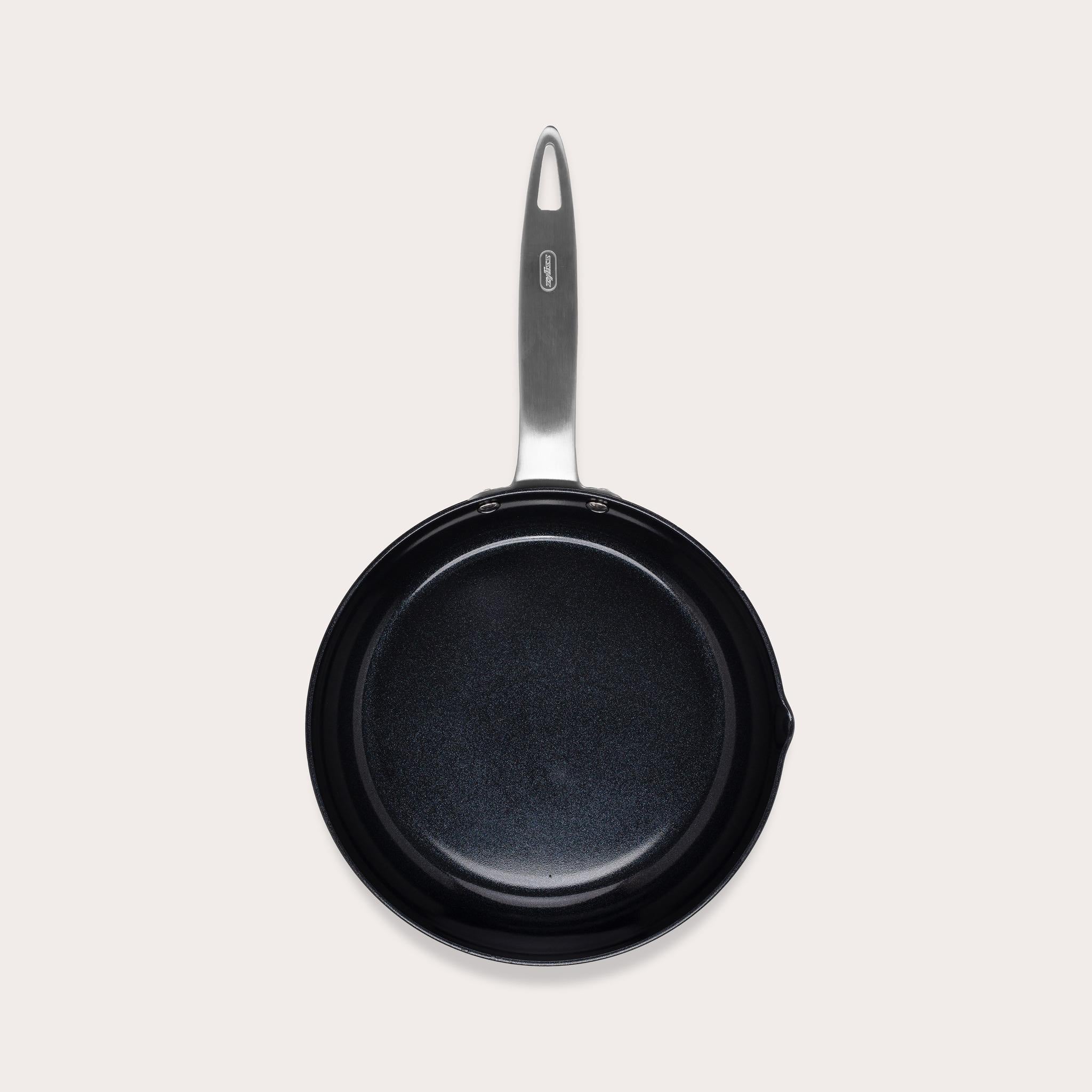 A black nonstick frying pan with a silver handle, viewed from above, against a plain light background.
