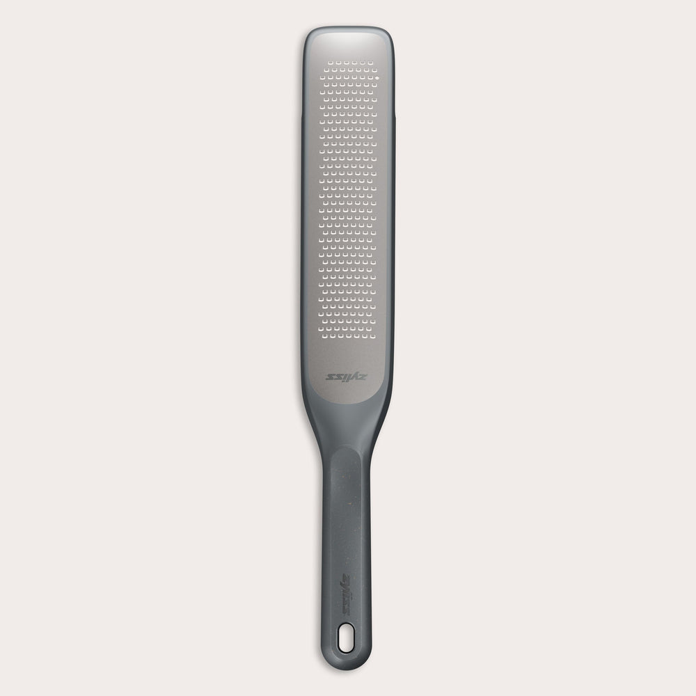 #belugagrey The Zyliss Rasp Grater is a long, rectangular foot file with a gray handle and textured metal surface for removing calluses and dead skin. The handle features a hanging hole for easy storage. 