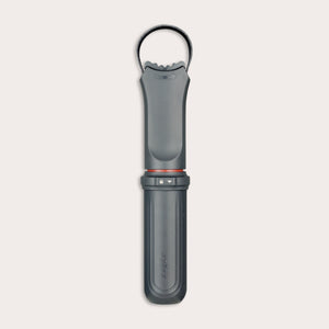 The Zyliss Jar Opener, shown vertically against a light background, is a black and gray handheld tool with a textured grip, integrated locking mechanism, circular top loop, and comes with a protective blade sheath. 