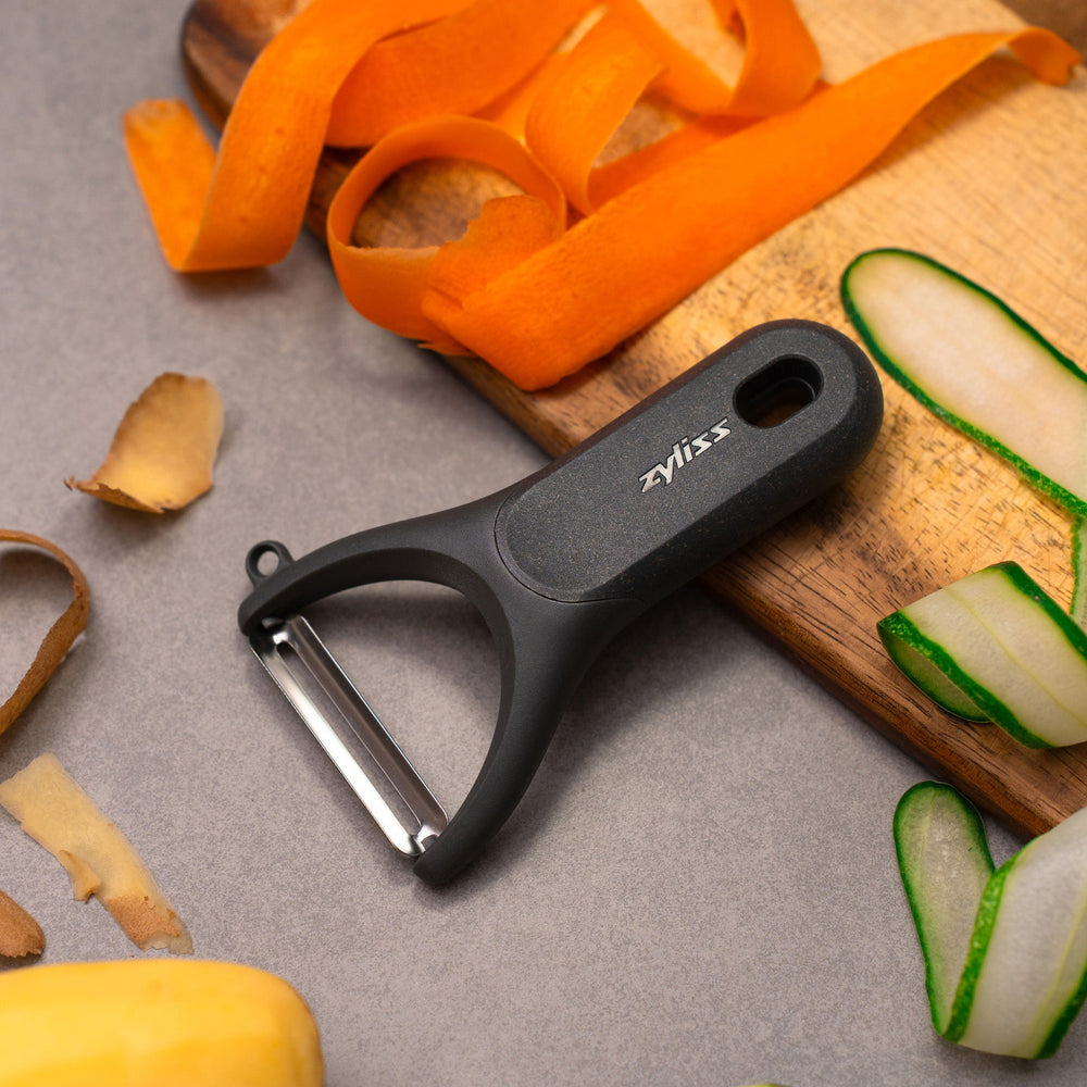 A Zyliss Y Peeler with a stainless steel swivel blade, ergonomic handle, and end hole is shown in black on a plain white background. 