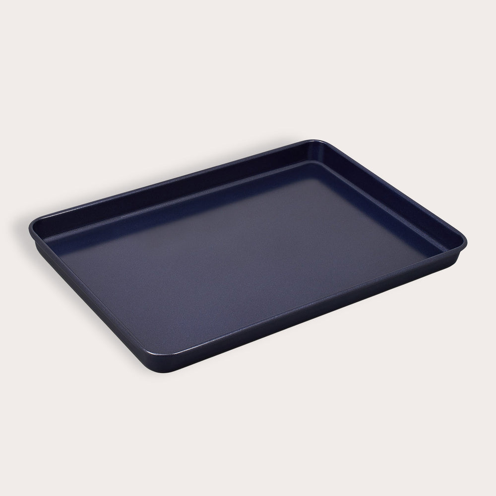 A Zyliss Durable Non-Stick Baking Tray, dark-colored with raised edges and made from non-stick carbon steel, is displayed against a plain light background.