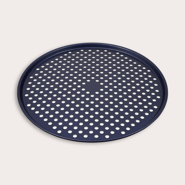 The Zyliss Durable Non-Stick Pizza Tray is a round, dark blue metal tray with raised edges and a perforated base featuring evenly spaced holes for optimal baking, shown against a plain light background.