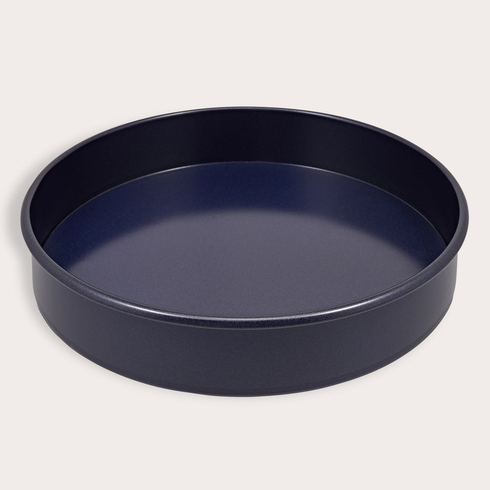 A round, dark Zyliss Durable Non-Stick Removable Base Cake Pan with high sides sits on a light surface, empty. Its smooth nonstick interior ensures easy release and effortless cleanup.