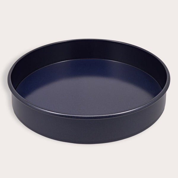 A round, dark Zyliss Durable Non-Stick Removable Base Cake Pan with high sides sits on a light surface, empty. Its smooth nonstick interior ensures easy release and effortless cleanup.