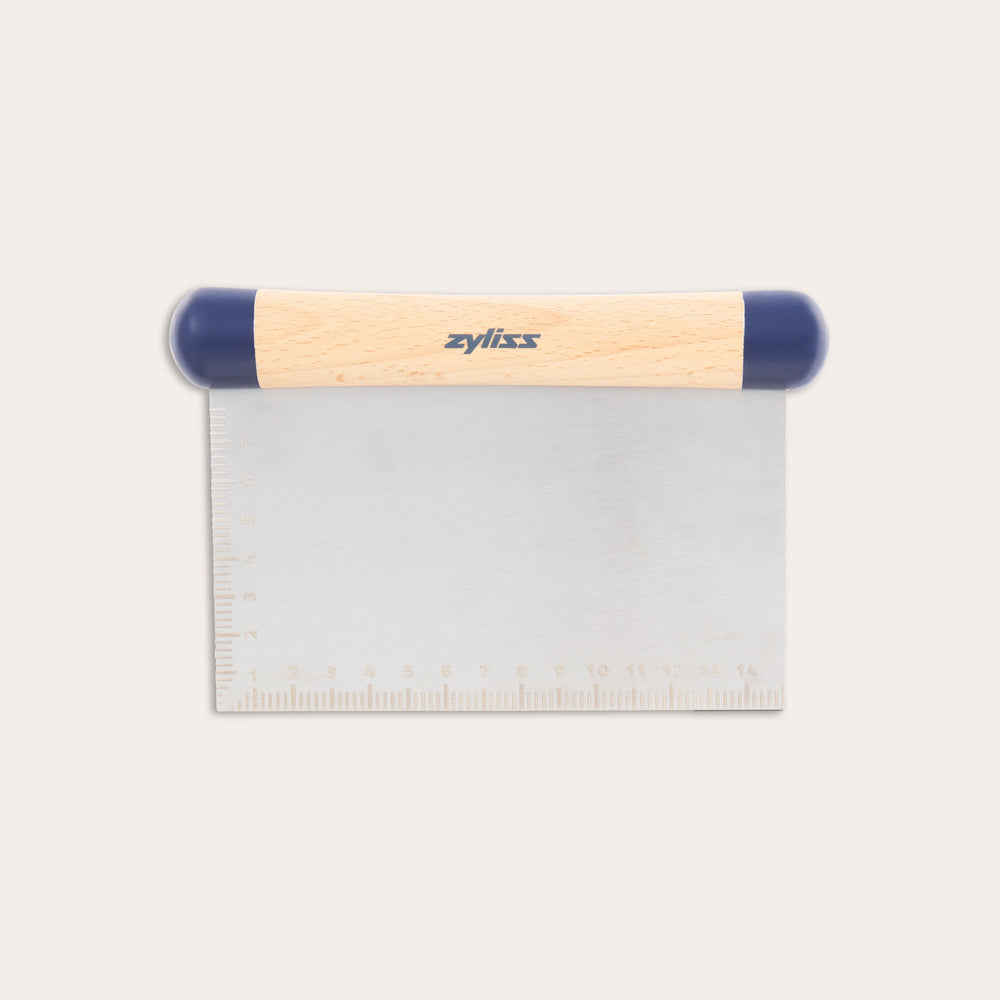 The Zyliss Beech Wood Bench Scraper features a beech wood handle, blue plastic ends, and a metal blade with an etched ruler—a versatile tool for baking tasks. 