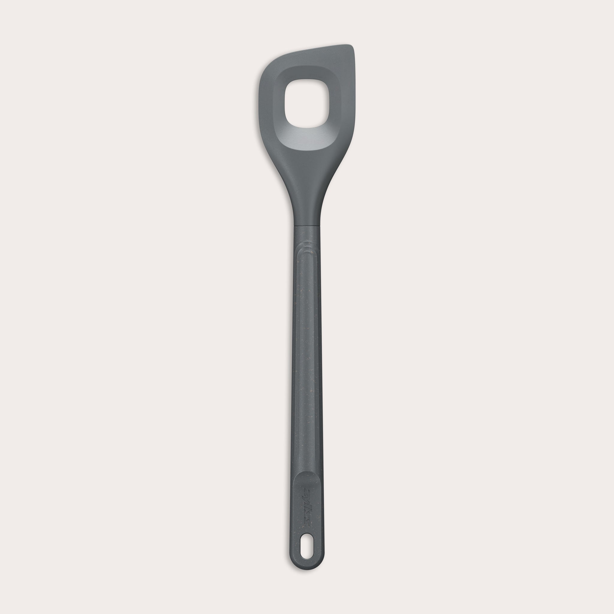 The Zyliss Angled Mixing Spoon is a gray silicone utensil with an ergonomic handle and a rectangular hole in the head, designed for non-stick cookware. Shown on a plain white background. 