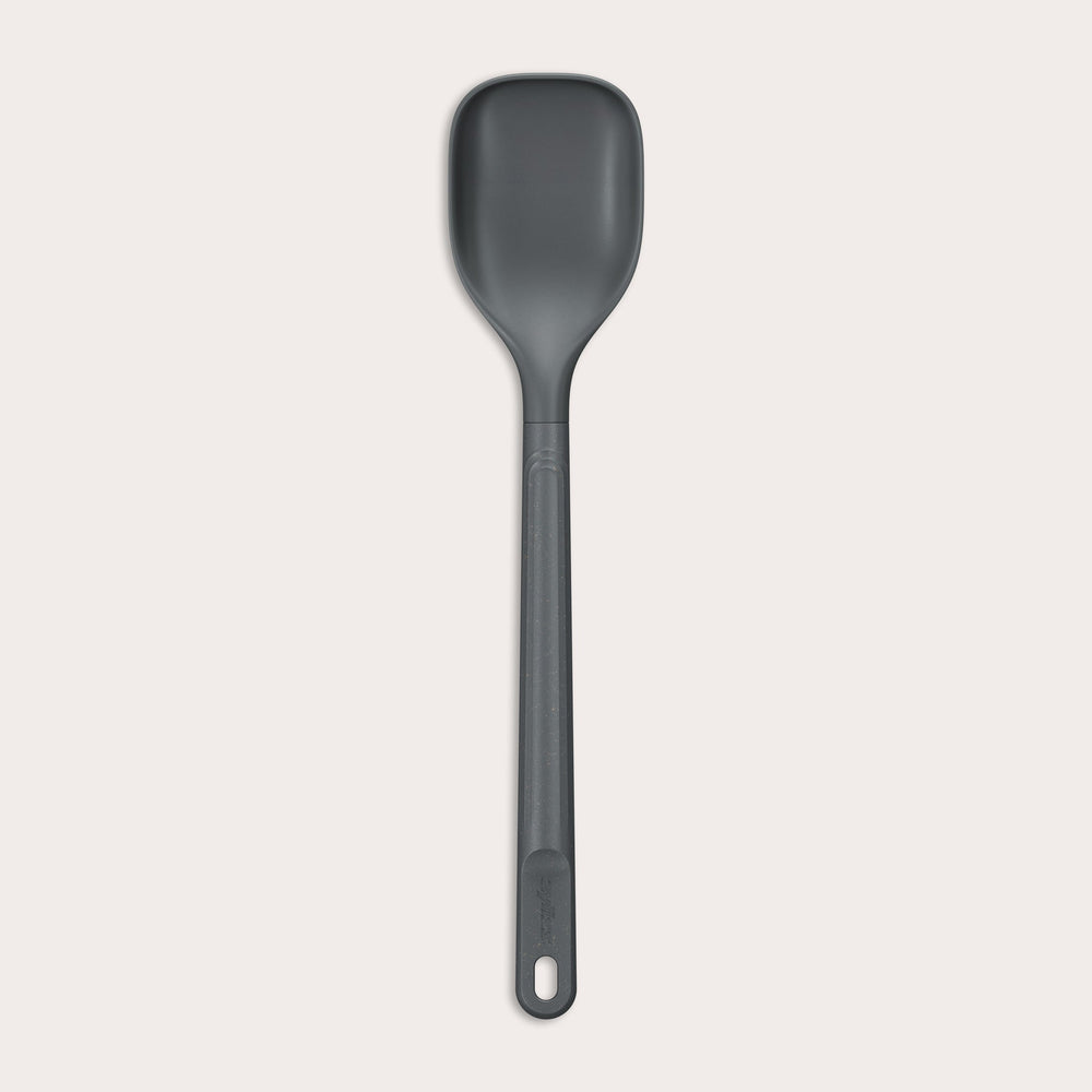 #medium The Zyliss Spoon is a dark gray, heat-resistant silicone utensil with a long handle and end hole, ideal for cooking or serving. Shown against a plain light background. #Medium