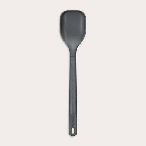 #medium The Zyliss Spoon is a dark gray, heat-resistant silicone utensil with a long handle and end hole, ideal for cooking or serving. Shown against a plain light background. #Medium