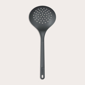 The Zyliss Skimmer features a black, round perforated head and an ergonomic, heat-resistant handle with a hanging hole, displayed against a plain light background. 