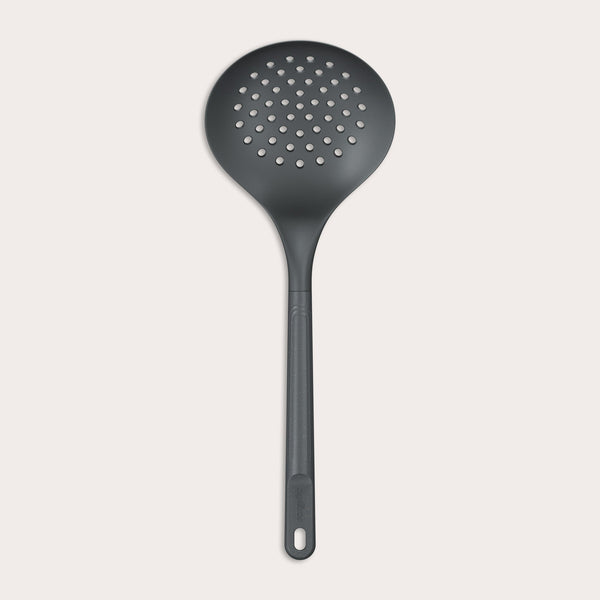 The Zyliss Skimmer features a black, round perforated head and an ergonomic, heat-resistant handle with a hanging hole, displayed against a plain light background. 