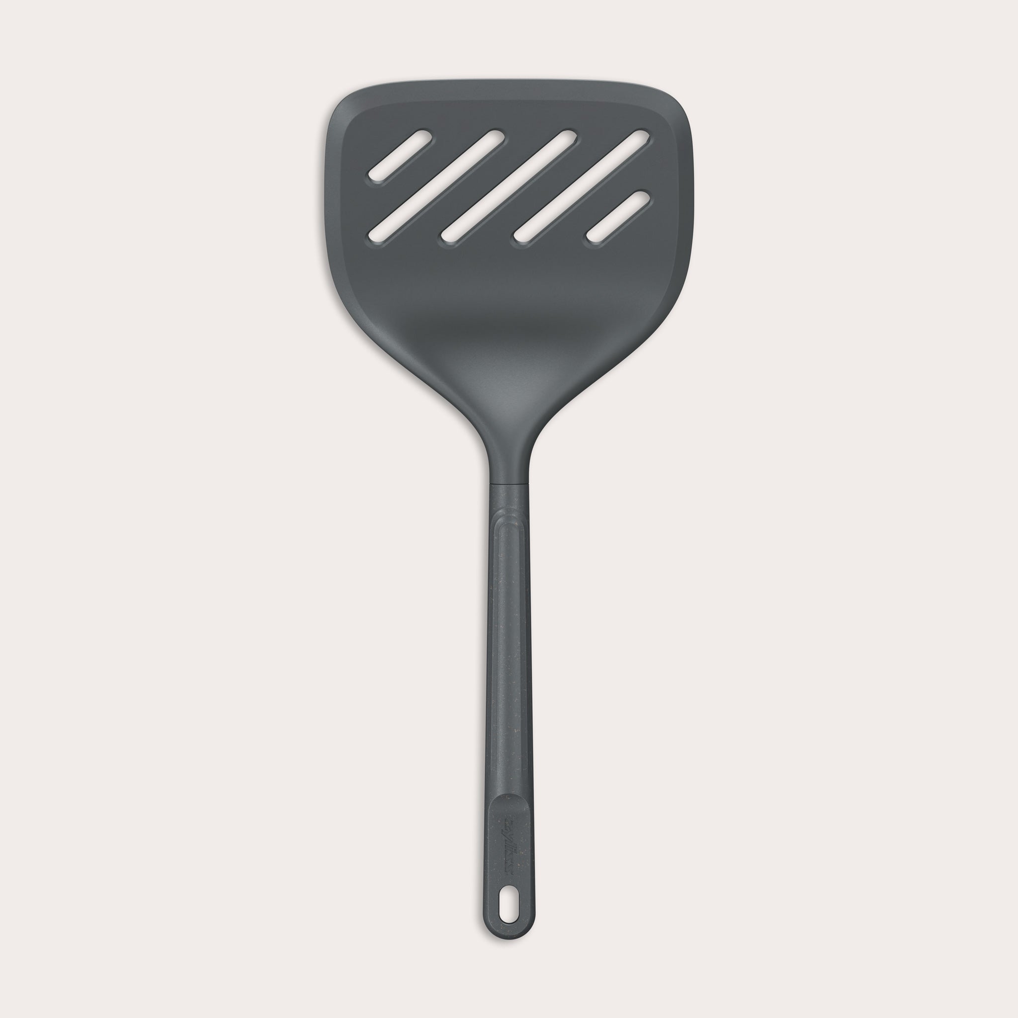 A Zyliss Turner XL slotted spatula in black, featuring a wide square head with three diagonal slots, ergonomic handle, and heat-resistant design is displayed against a plain light background. 