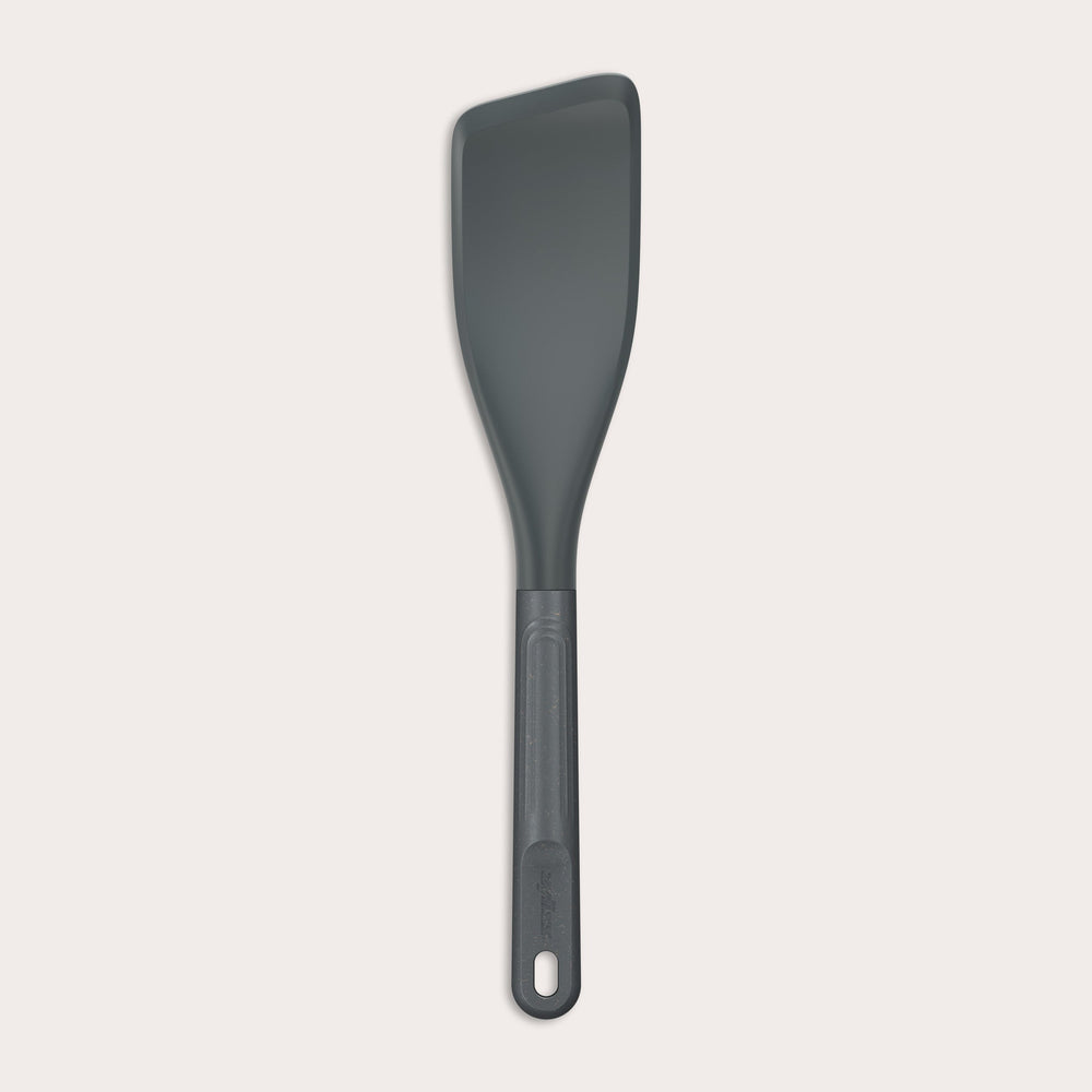 The Zyliss Easy Lift Turner is a gray, heat-resistant silicone utensil with a rectangular, angled head and long handle with hanging hole—perfect for non-stick cookware. Shown on a plain white background. 