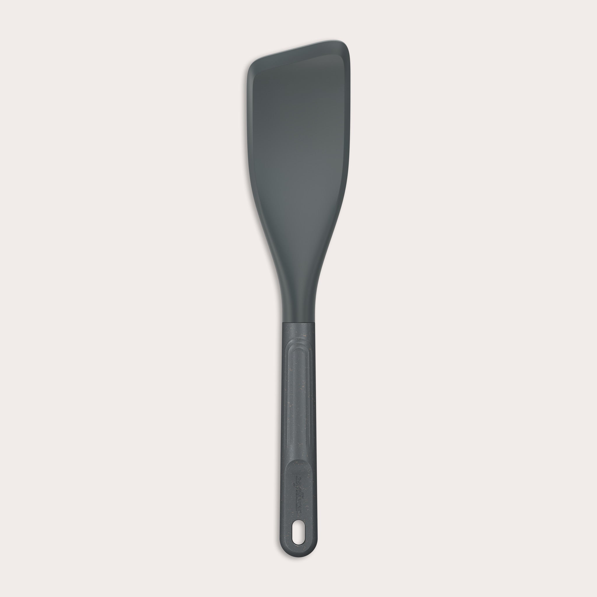 The Zyliss Easy Lift Turner is a gray, heat-resistant silicone utensil with a rectangular, angled head and long handle with hanging hole—perfect for non-stick cookware. Shown on a plain white background. 