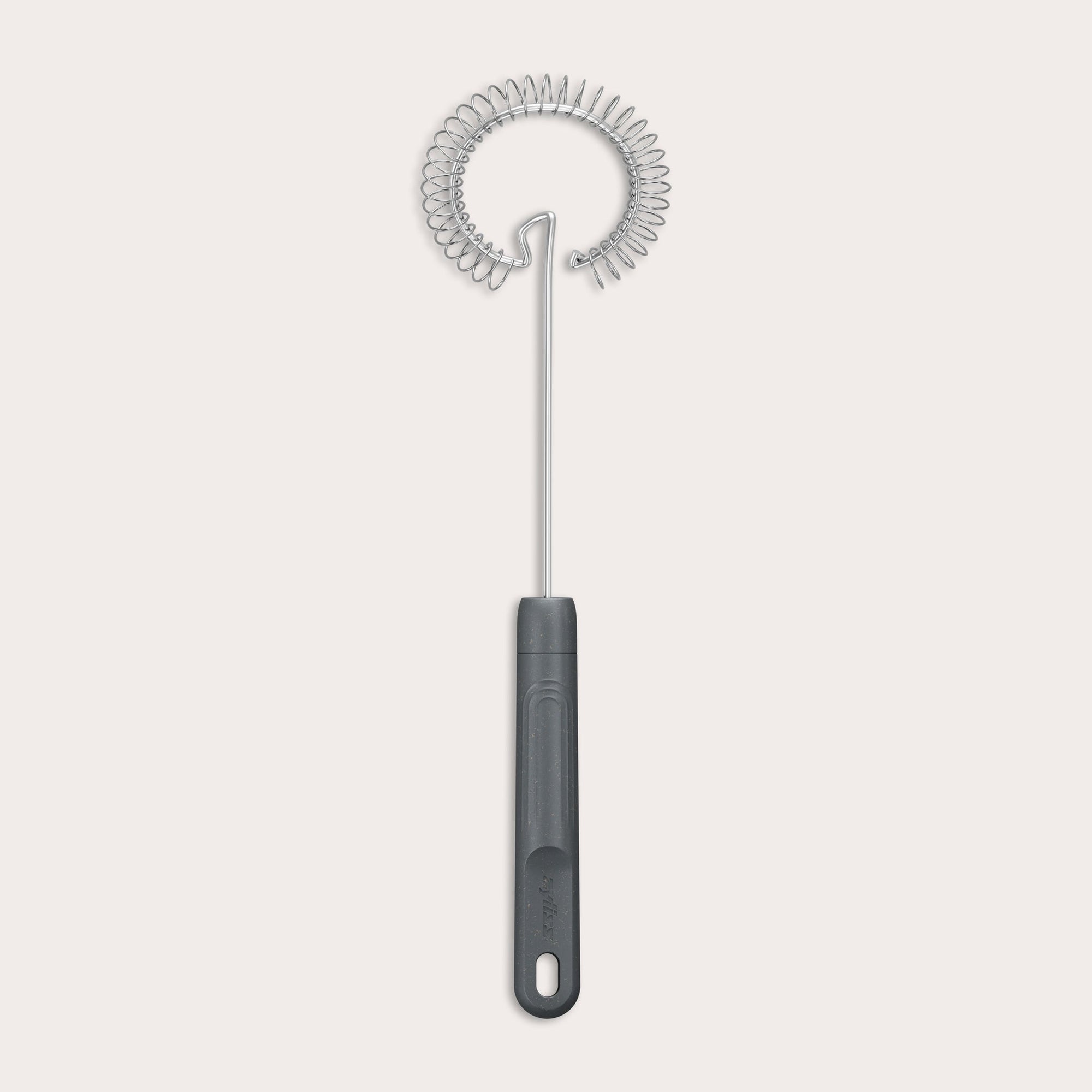 The Zyliss Gravy Whisk features a metal spiral and a dark plastic handle with a hanging hole. It is heat-resistant and shown against a plain light background. 