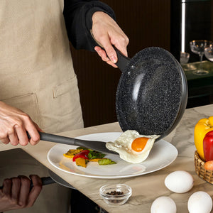 #20cm/8"
A person in an apron uses the Zyliss Ultimate Ceramic Fry Pan to slide a sunny-side-up egg onto roasted vegetables, surrounded by eggs, bell peppers, and a bowl of pepper on the kitchen counter.