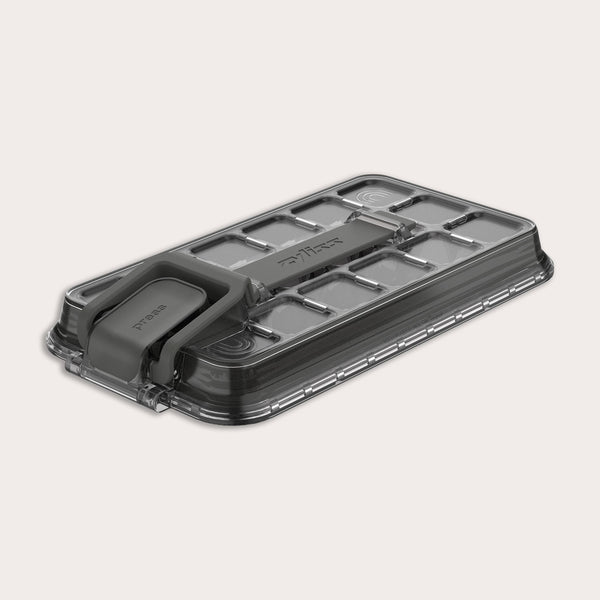 A rectangular, transparent plastic lid for the Zyliss Press & Pull Ice Cube Tray with a gray foldable handle, textured grid pattern, and "Zyliss" embossed on top, shown on a light background.