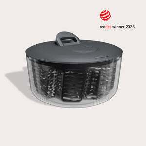 #large  A transparent Zyliss Easy Spin Salad Spinner with a dark gray lid and handle is shown, featuring AquaVent technology and a circular design. The image displays the “Red Dot Winner 2025” award logo in the corner.